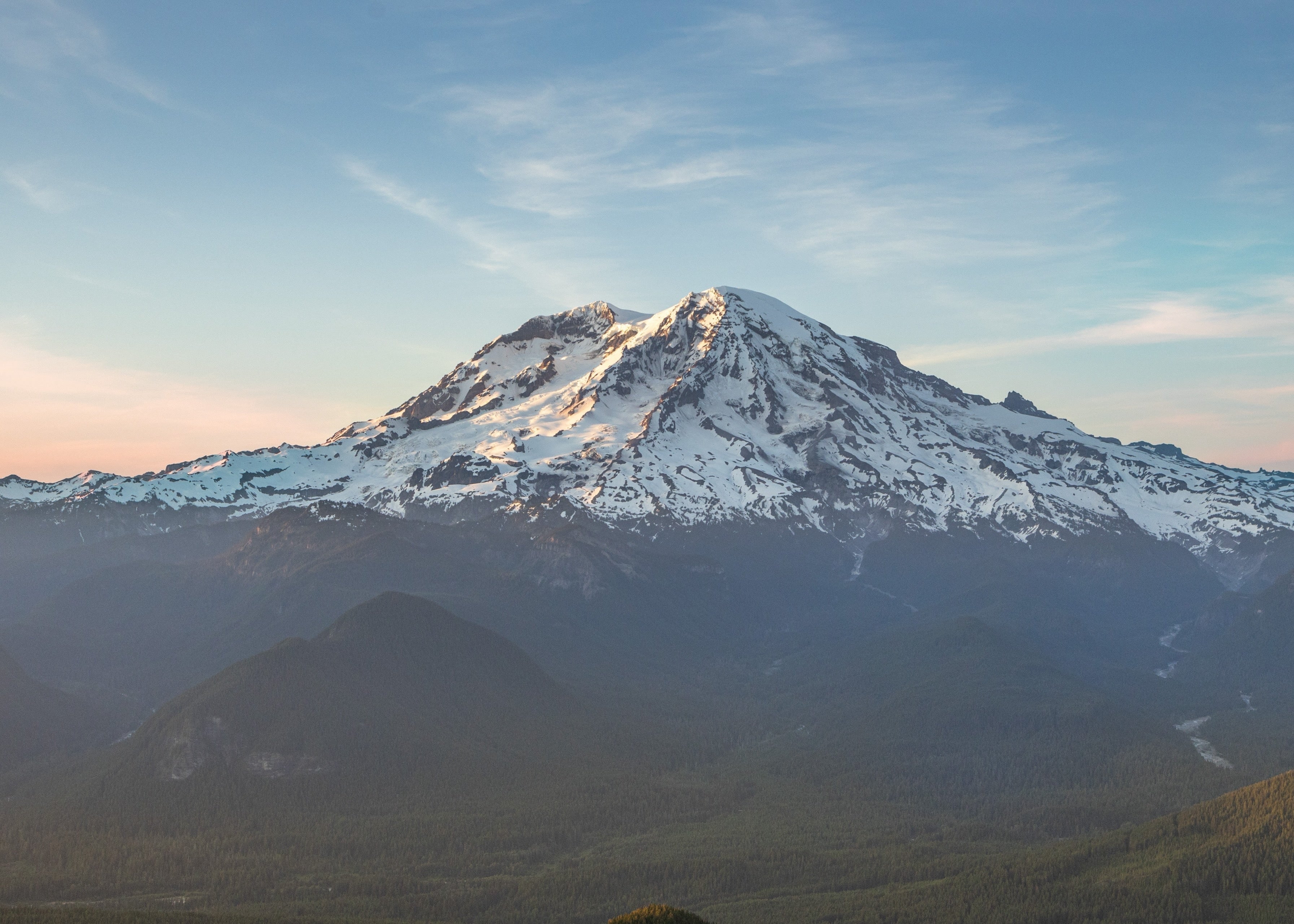 Mount Rainier at sunrise seen from High Rock, above forested ridgelines